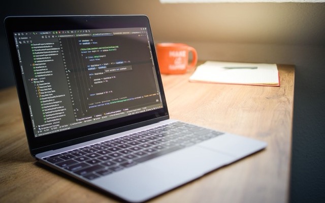 Web designer's workspace with a laptop showing code